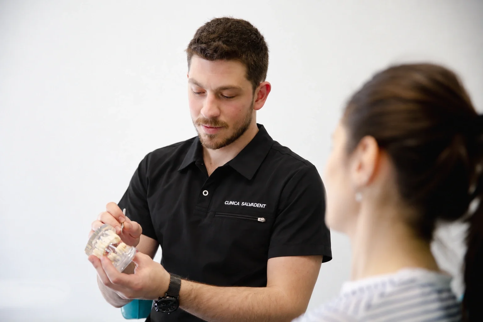 Medic care îi explică unei paciente, pe un model dentar transparent